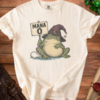 An off-white t-shirt featuring a graphic of a sleepy toad wearing a wizard hat and holding a Mana 0 sign.