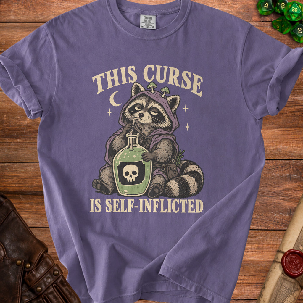 T-shirt with raccoon drinking from potion bottle, text says "This curse is self-inflicted".