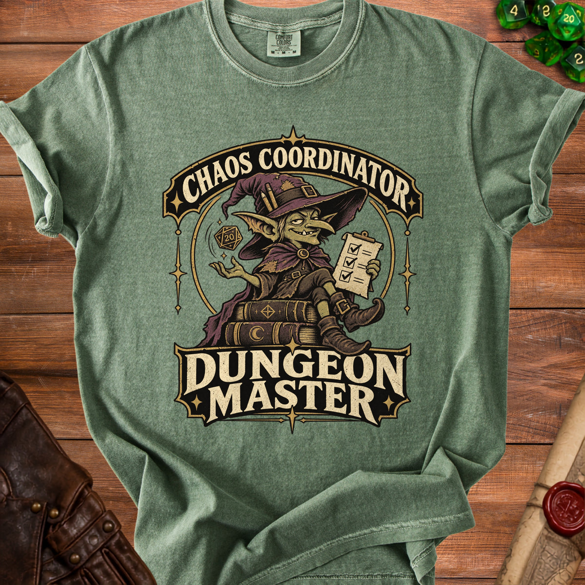A green t-shirt with a graphic of a goblin holding a checklist and dice, reading Chaos Coordinator Dungeon Master.