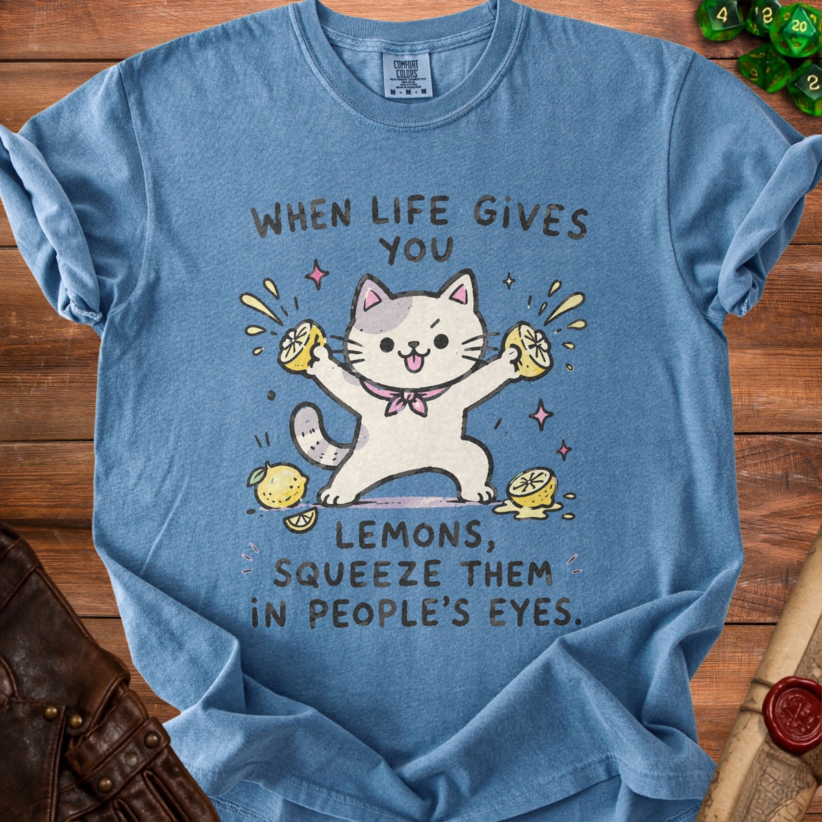 Blue t-shirt with a cartoon cat squeezing lemons and text "When life gives you lemons, squeeze them in people's eyes."