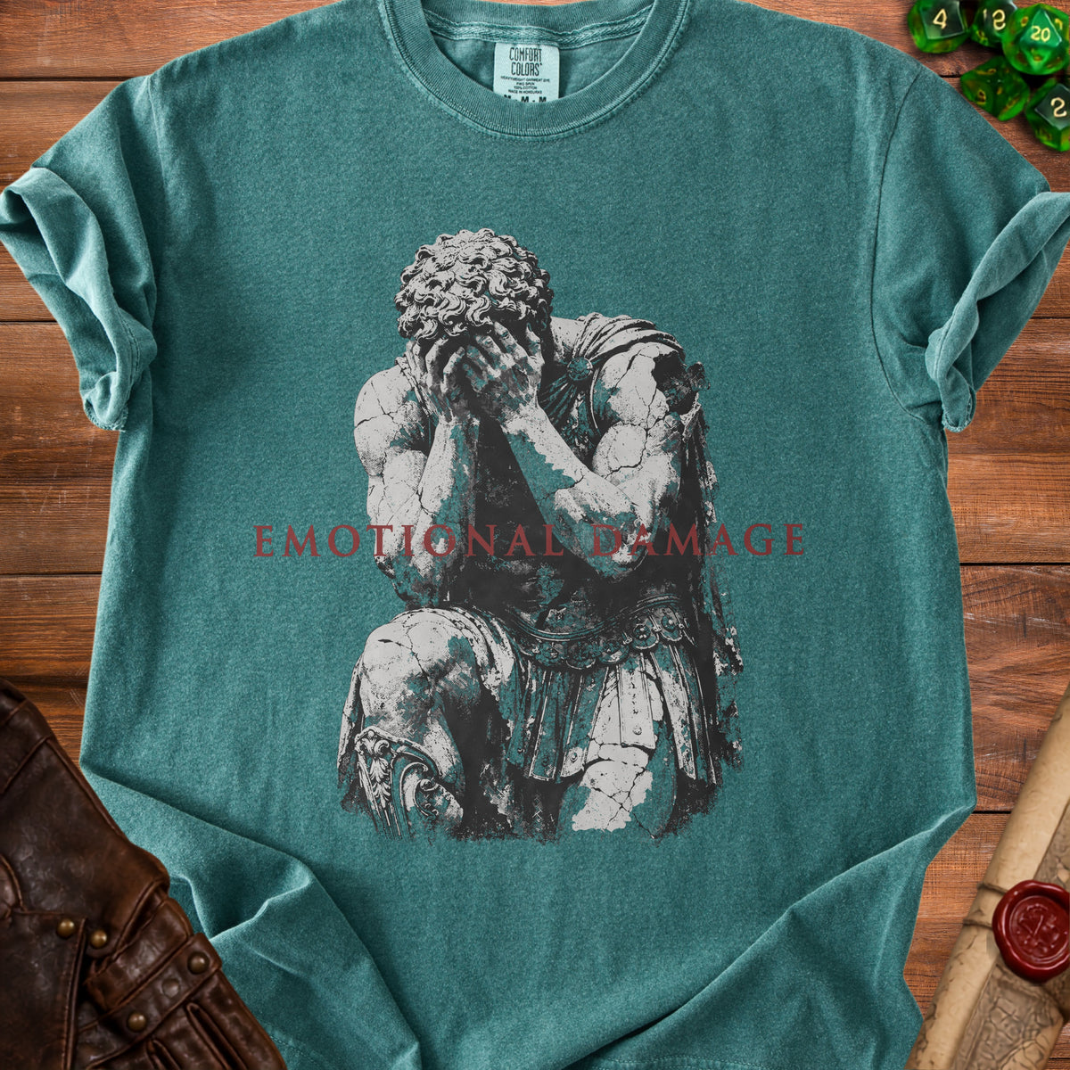 Teal t-shirt with a distressed graphic of a kneeling figure and the words "EMOTIONAL DAMAGE".