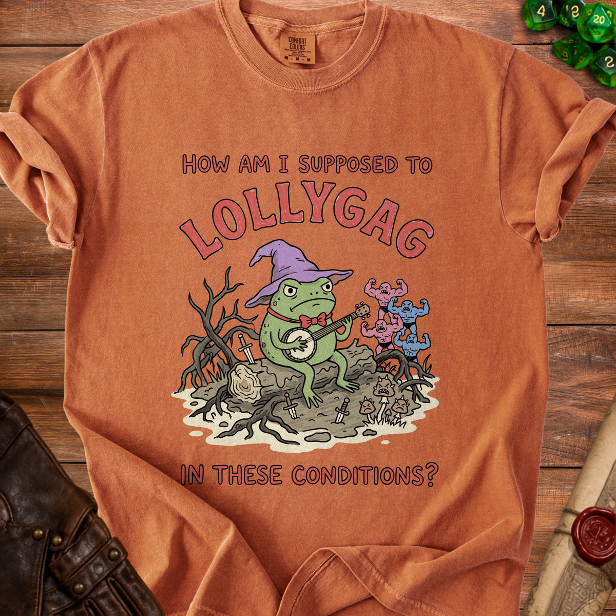 Orange t-shirt with a frog in a wizard hat playing banjo and text "How am I supposed to lollygag in these conditions?".