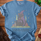 Blue t-shirt with a black cat in a witch hat brewing a potion.