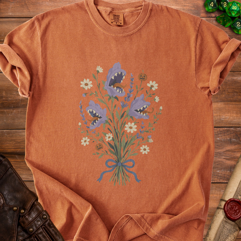 Orange t-shirt with a bouquet of purple shark-faced flowers and pumpkins.