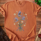 Orange t-shirt with a bouquet of purple shark-faced flowers and pumpkins.