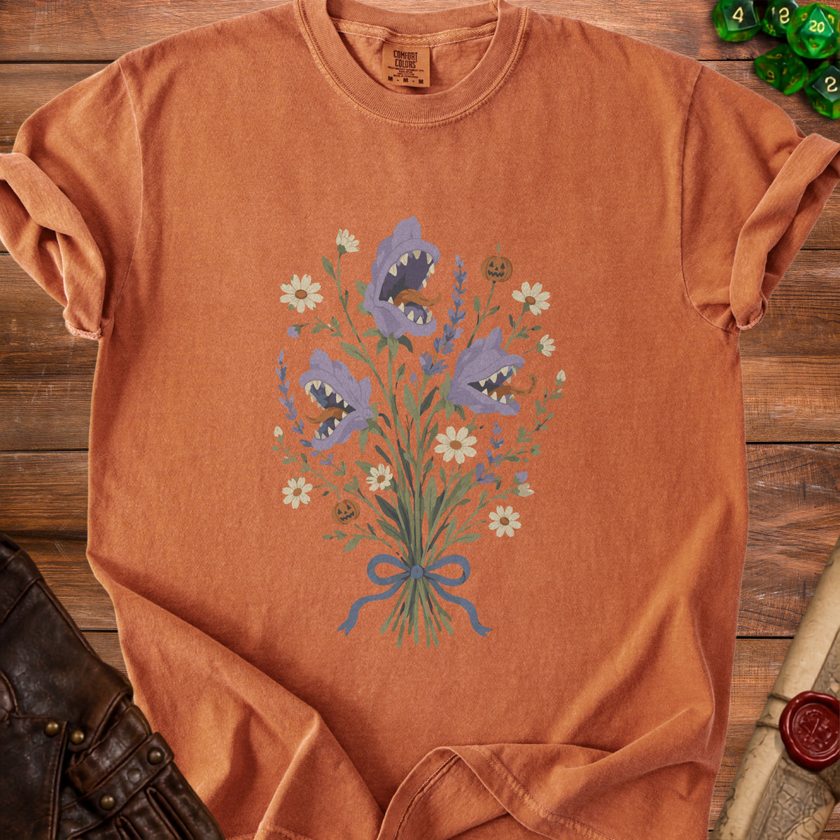 Orange t-shirt with a bouquet of purple shark-faced flowers and pumpkins.