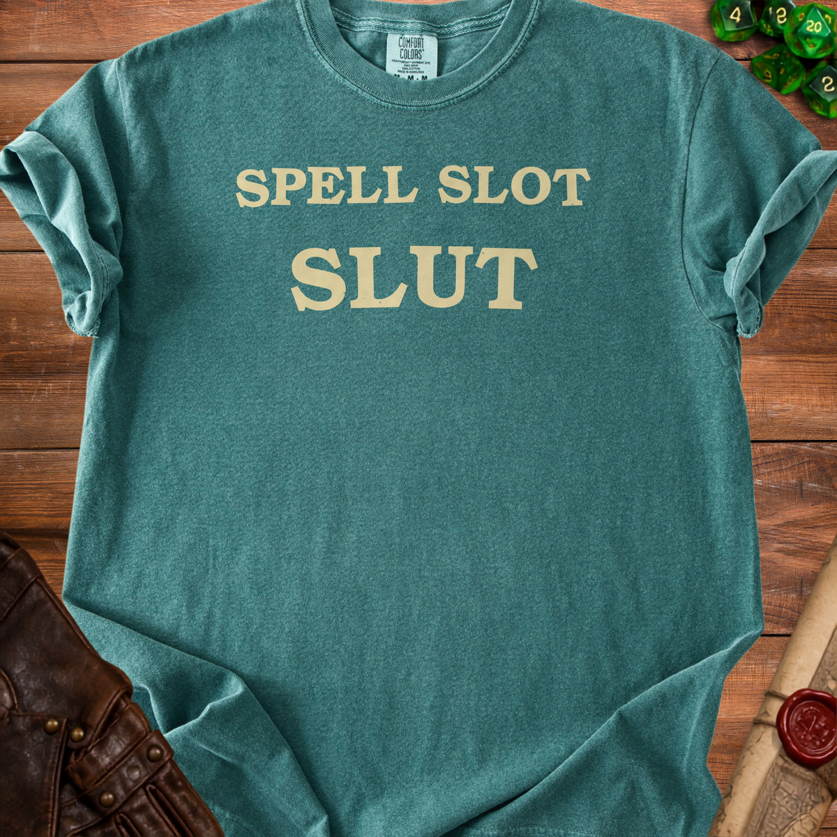 Teal t-shirt with beige text "SPELL SLOT SLUT" and "COMFORT COLORS" label.