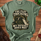 Green t-shirt with "The Plot Thickens, My Patience Does Not" text and fantasy art.