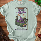 Light teal t-shirt with a graphic reading "Warning: May Cast Sarcasm At Will."
