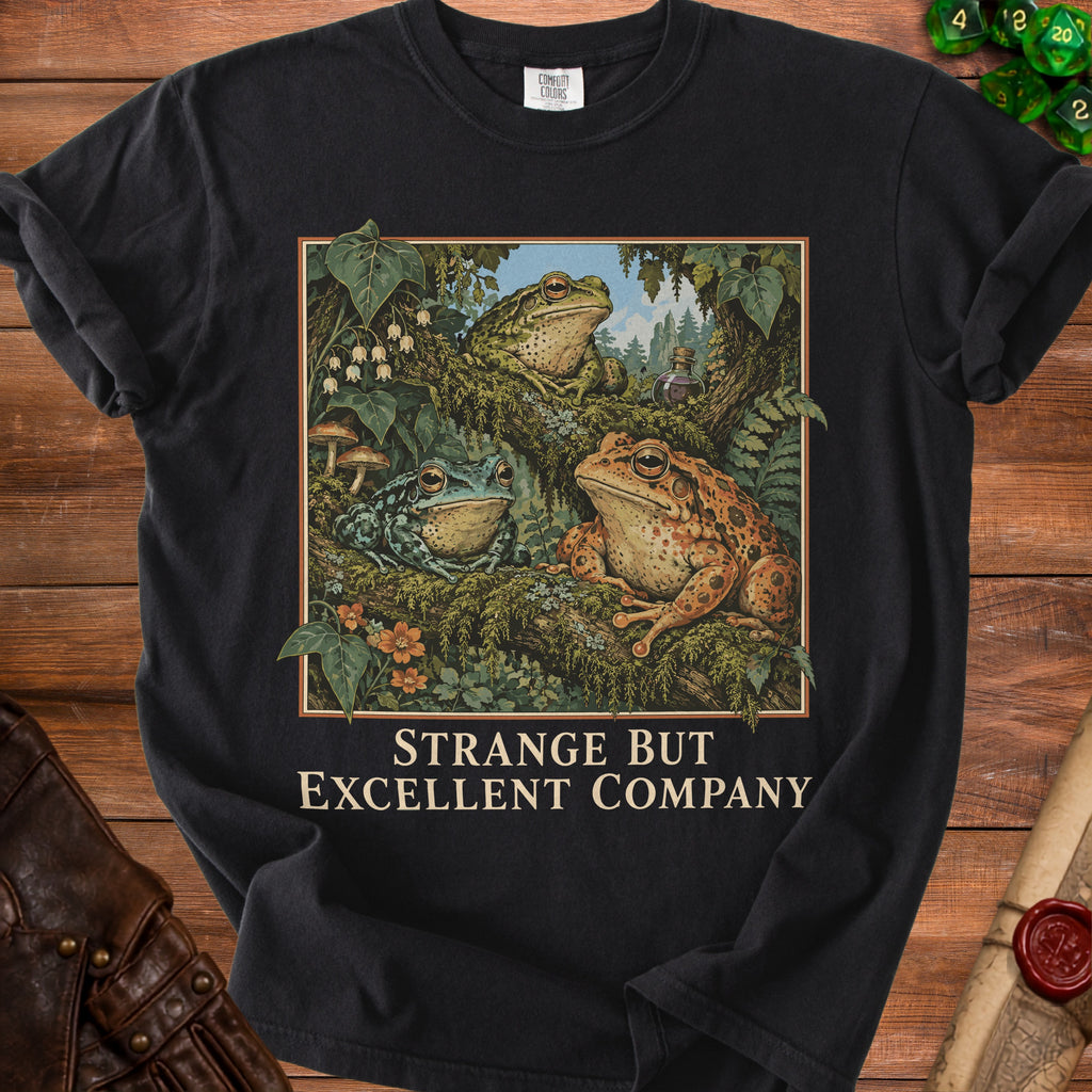 T-shirt with three frogs, ferns, mushrooms, and text "STRANGE BUT EXCELLENT COMPANY".