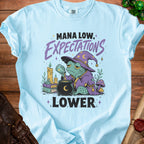 Light blue t-shirt with a wizard frog graphic and text "Mana Low, Expectations Lower".