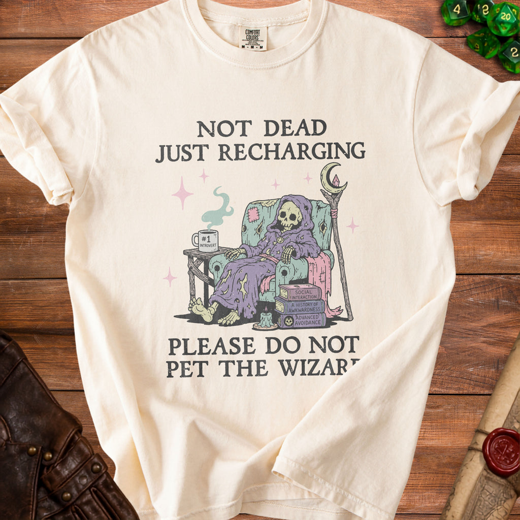 Cream t-shirt with "Not Dead Just Recharging" and a skeleton wizard graphic.