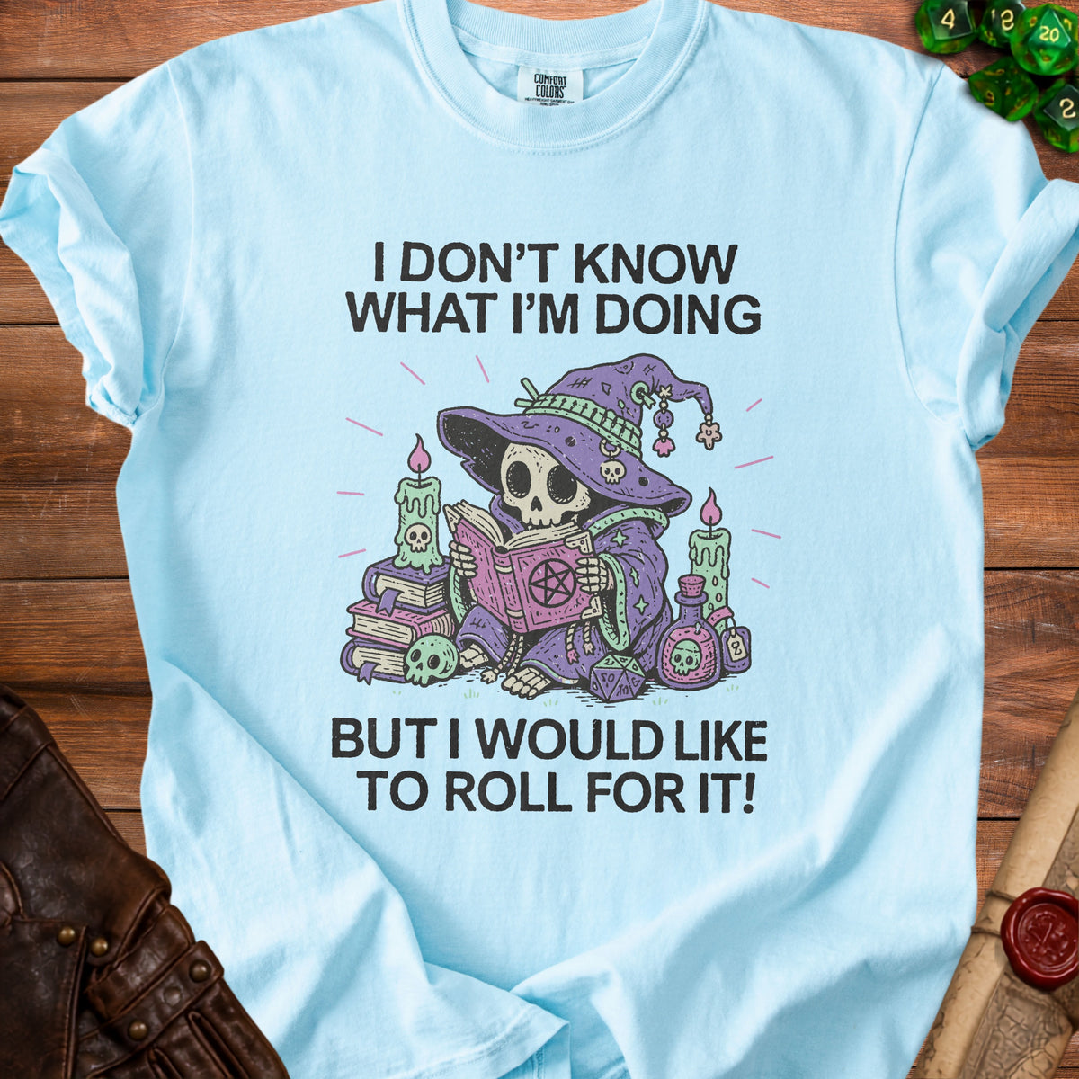 Light blue t-shirt with skull wizard reading a book and text "I DON'T KNOW WHAT I'M DOING BUT I WOULD LIKE TO ROLL FOR IT!"