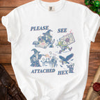 White t-shirt graphic with wizards, goblins, and text reading "Please See Attached Hex".