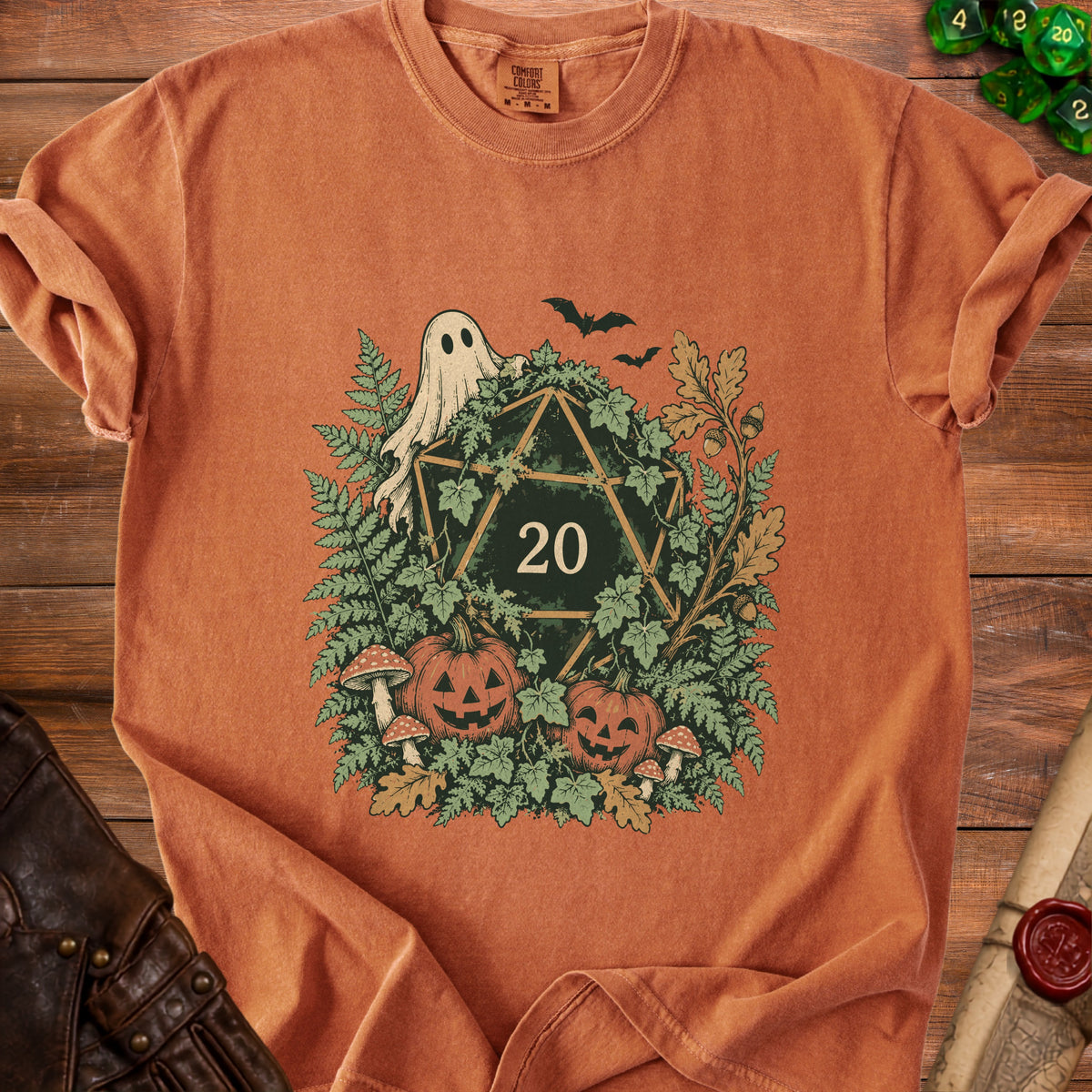 Orange t-shirt with a Halloween-themed D20 dice graphic surrounded by pumpkins and leaves.