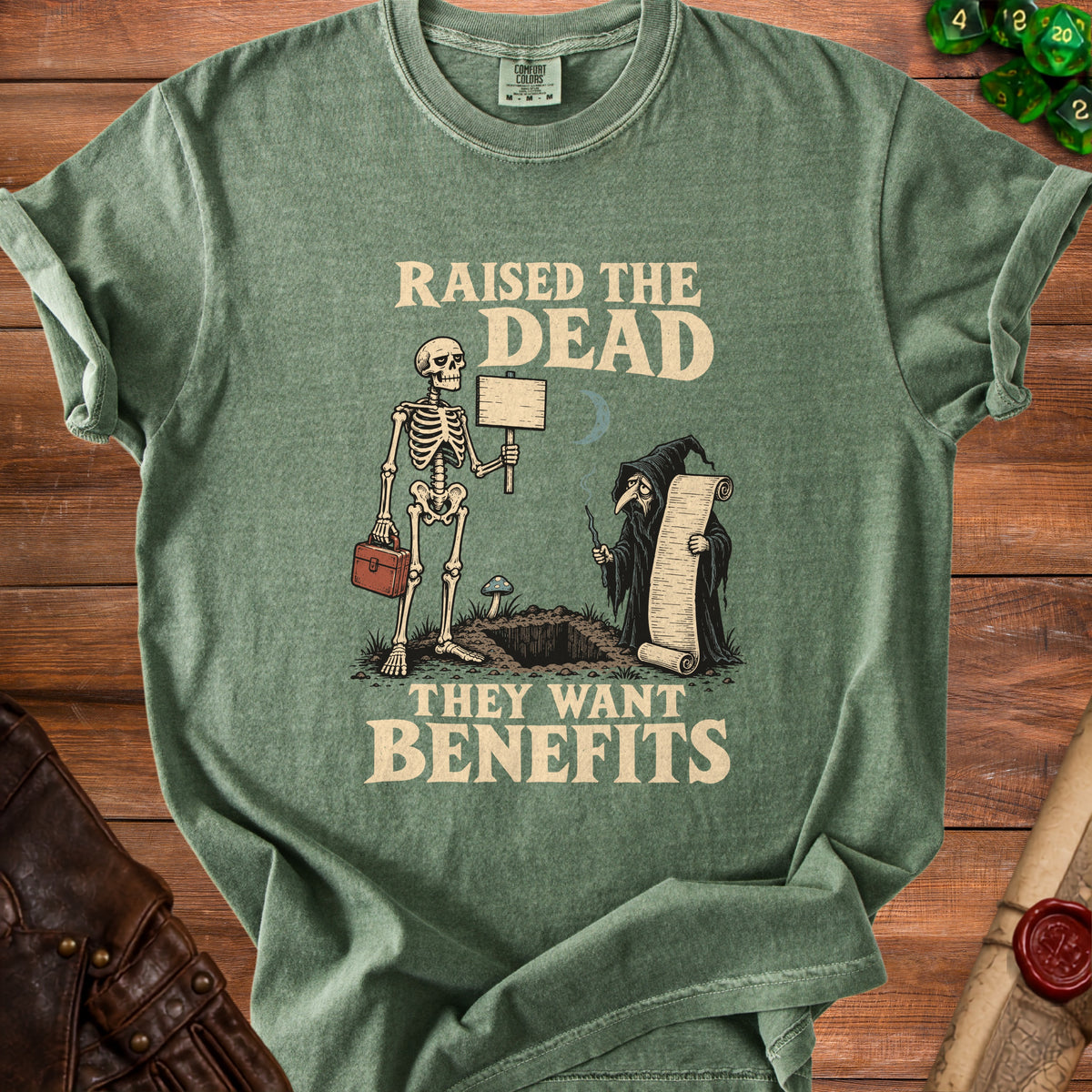 Green t-shirt with skeleton and grim reaper illustration reading "Raised the Dead" and "They Want Benefits."
