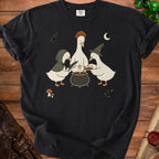 Black t-shirt featuring a graphic of three cartoon ducks wearing witch hats brewing a potion.