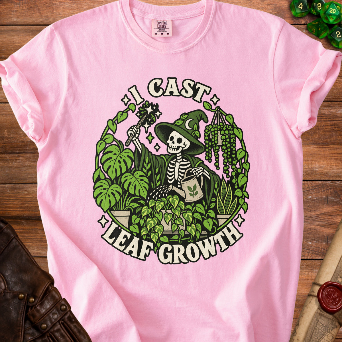 Pink t-shirt with skeleton wizard watering plants, text "I CAST LEAF GROWTH".