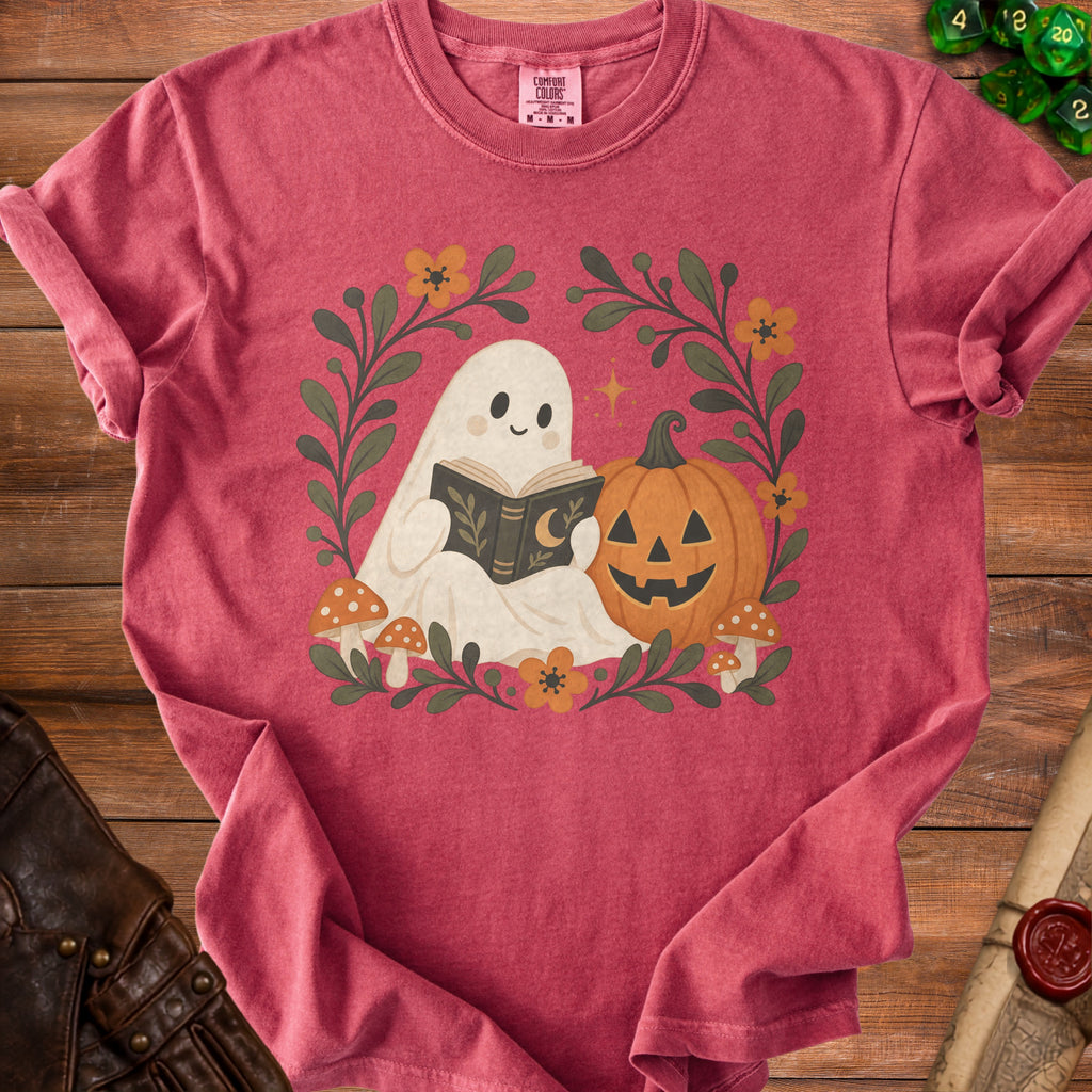 Ghost reading book with pumpkin, mushrooms, and flowers on a pink t-shirt.