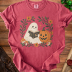 Ghost reading book with pumpkin, mushrooms, and flowers on a pink t-shirt.