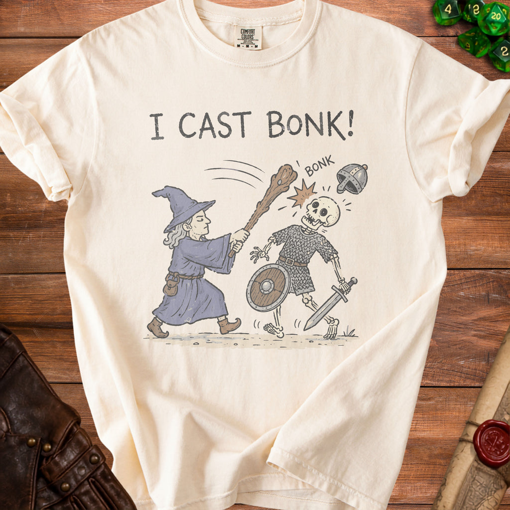 Cream t-shirt with wizard hitting skeleton with club, text "I CAST BONK!".