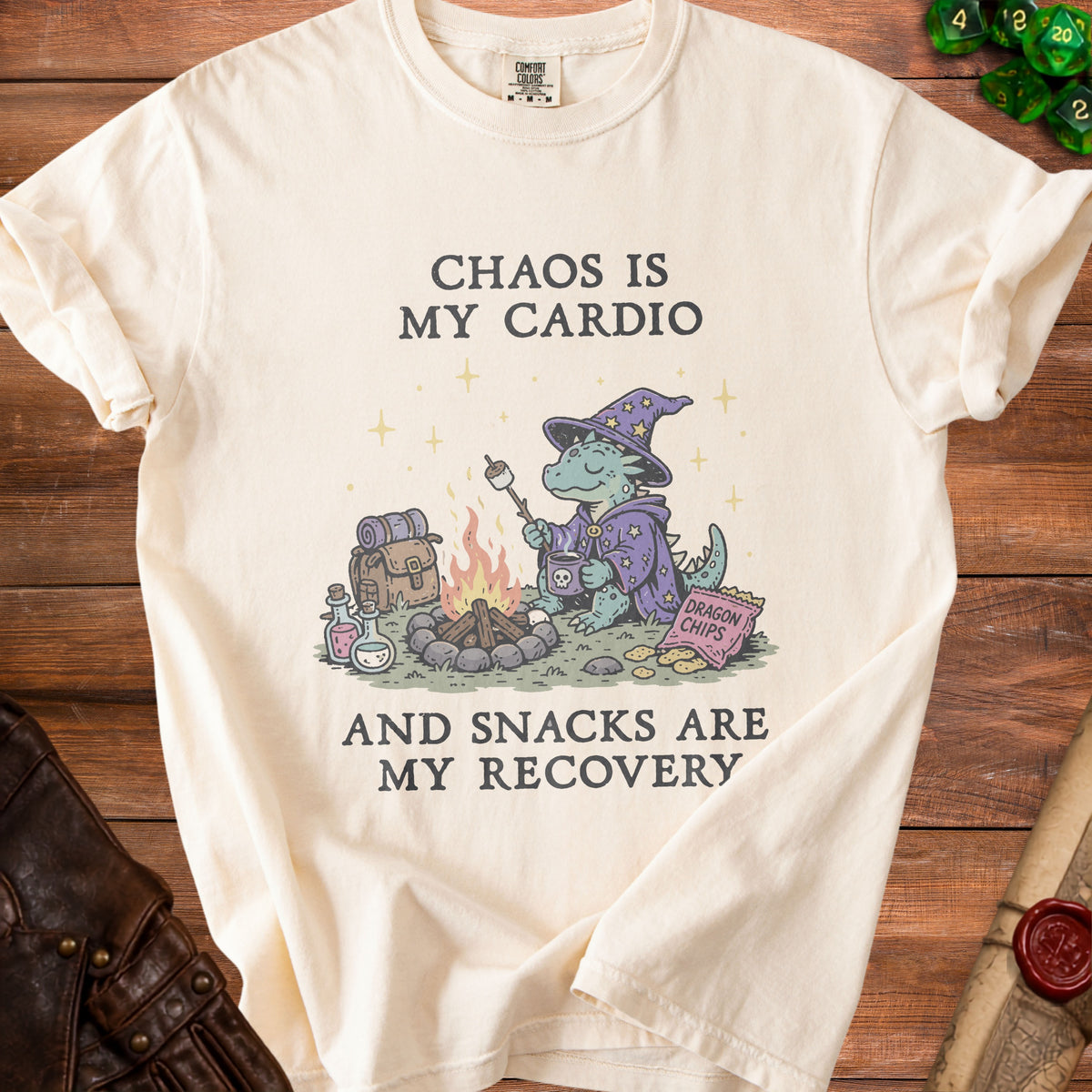 Cream t-shirt with a dragon roasting a marshmallow by a campfire, text reads "Chaos is my cardio and snacks are my recovery".