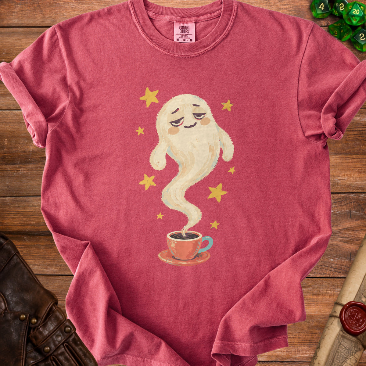 Pink t-shirt with a watercolor graphic of a tired ghost drinking coffee surrounded by stars.