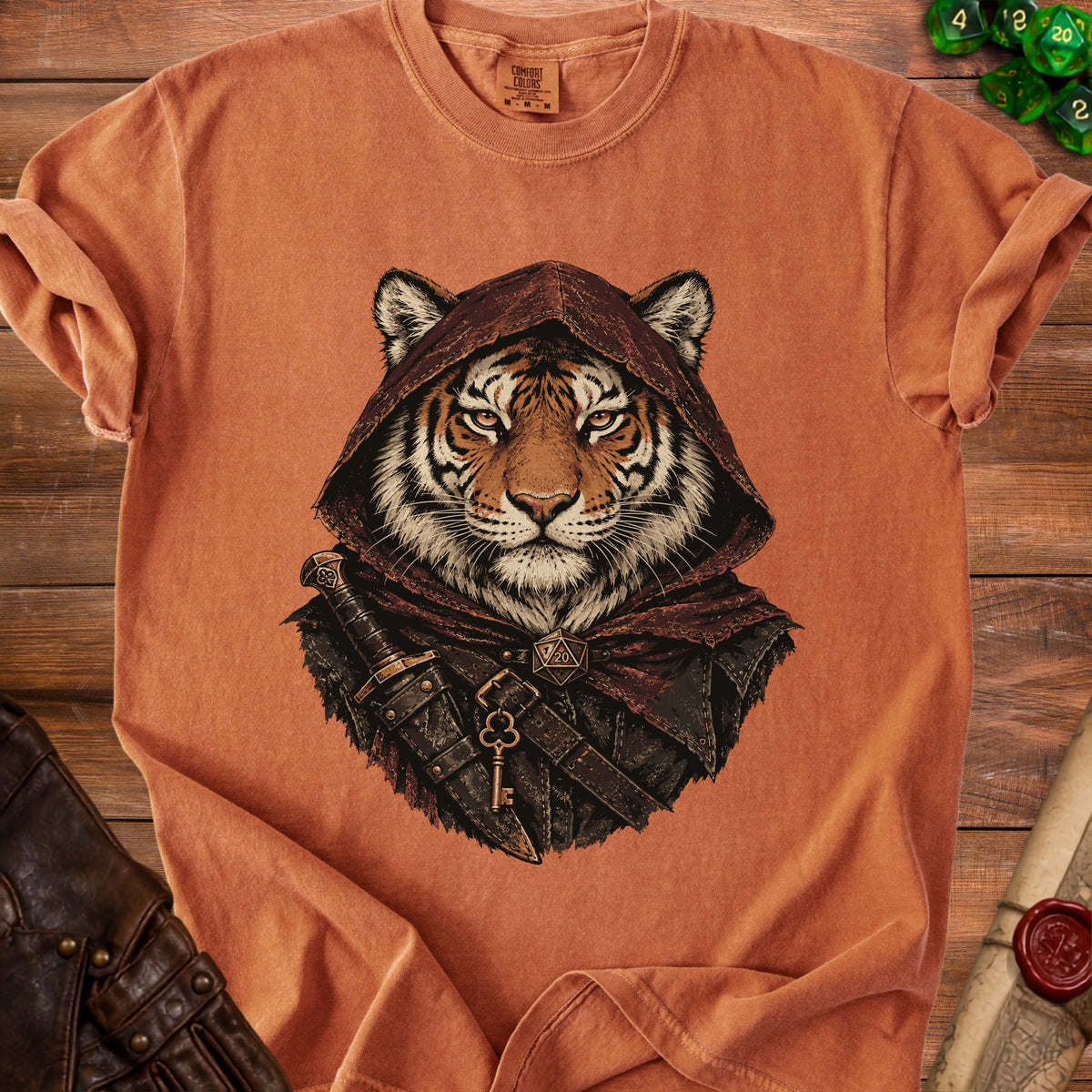 An orange t-shirt featuring a graphic of a hooded tiger rogue with a dagger and key.