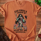 Orange t-shirt with graphic of a witch and cat, reading "God forbid a woman be weird hot and whimsical."
