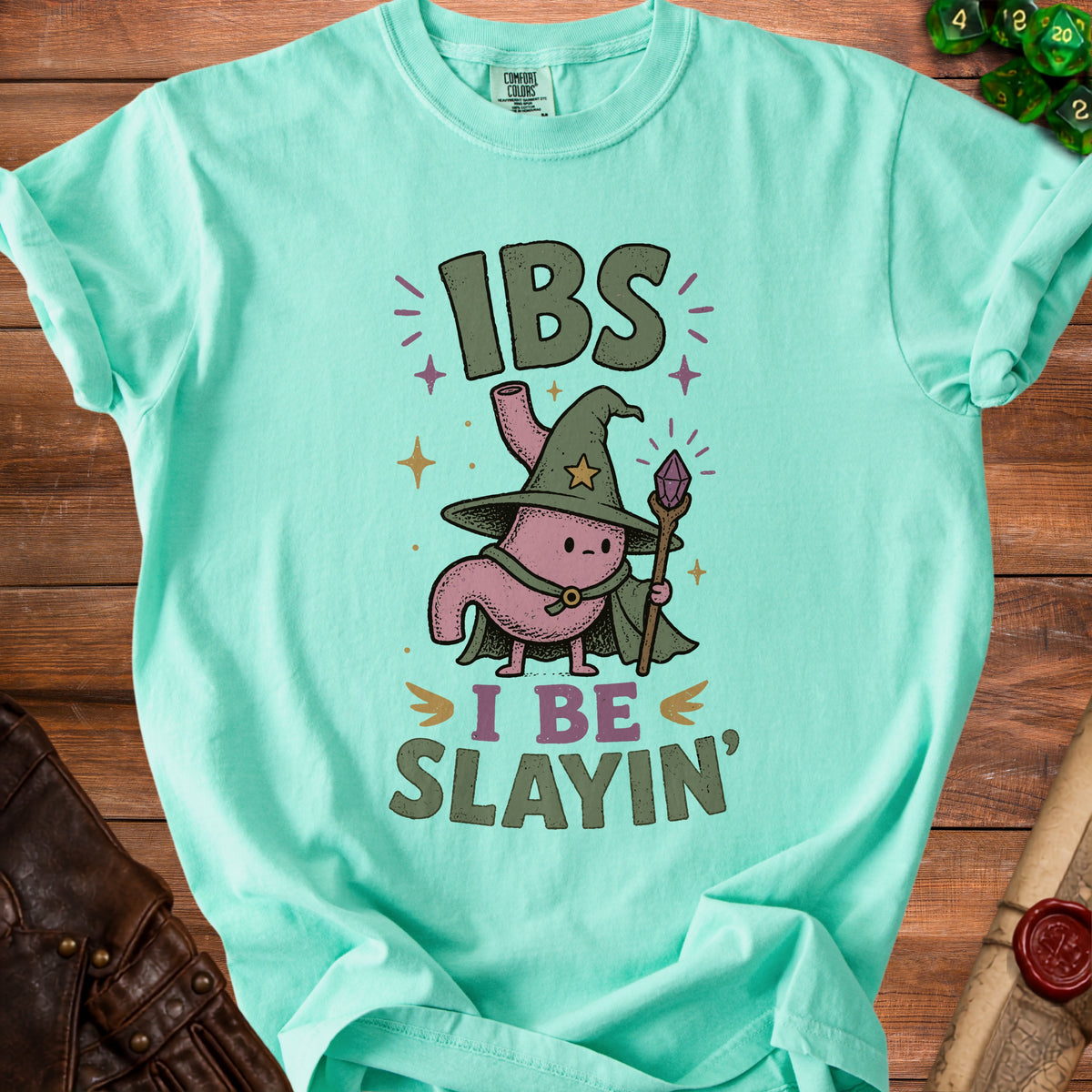 Mint green t-shirt with a cartoon stomach wearing a wizard hat and saying "IBS I Be Slayin'".