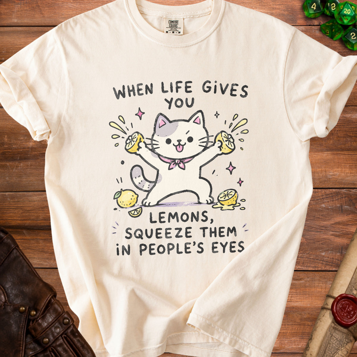 Cream t-shirt with cartoon cat squeezing lemons and text "When life gives you lemons, squeeze them in people's eyes."