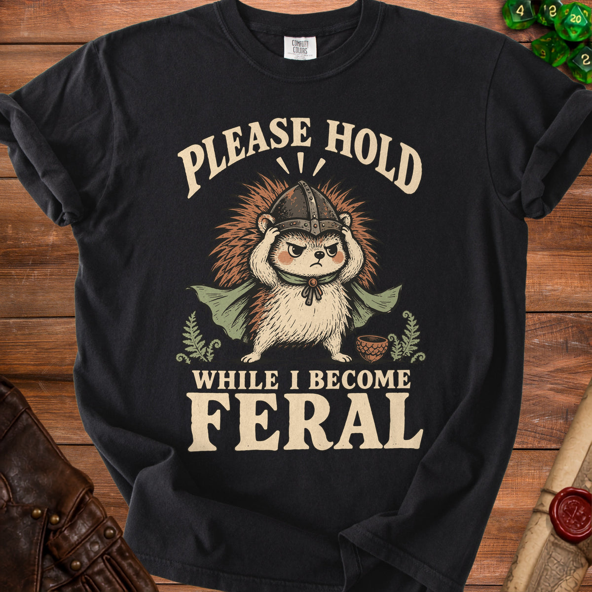 Black t-shirt with hedgehog in viking helmet and cape, text says "Please Hold While I Become Feral".