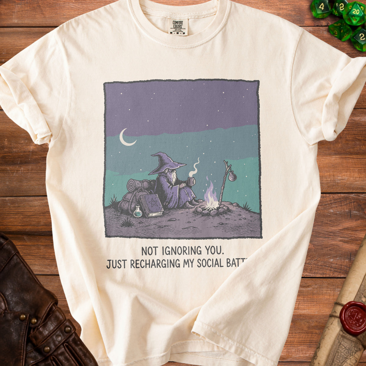 Cream t-shirt with a wizard by a campfire and text "NOT IGNORING YOU. JUST RECHARGING MY SOCIAL BATT".
