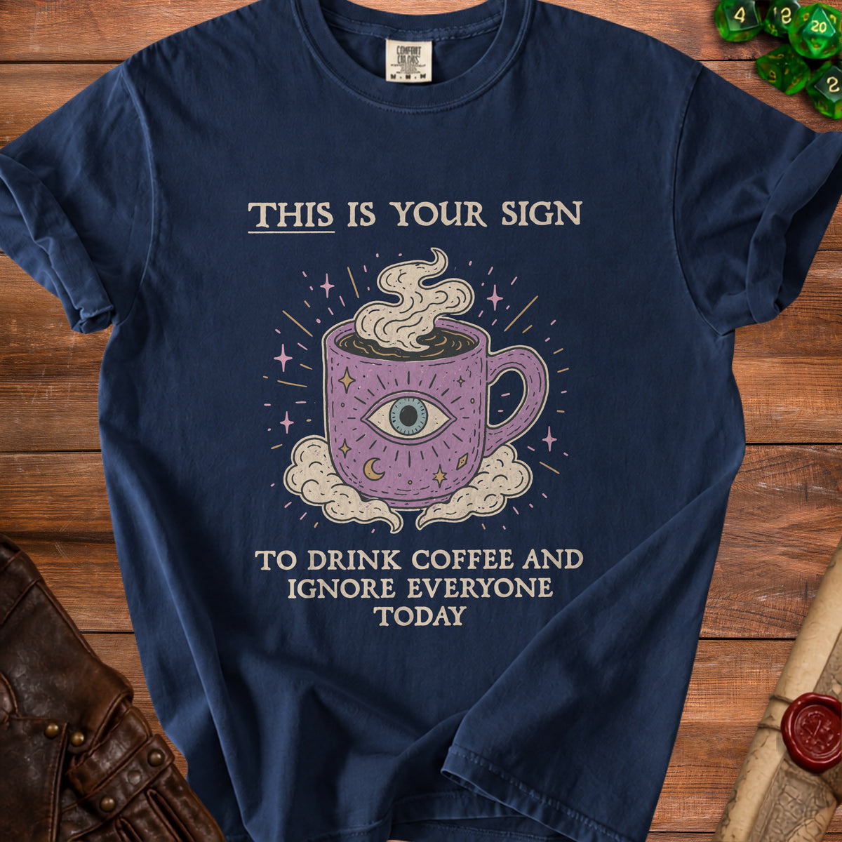 Navy t-shirt with "This is your sign to drink coffee and ignore everyone today" text and mystical coffee cup graphic.
