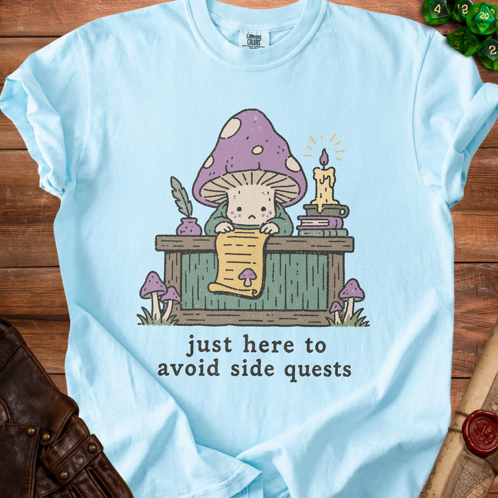 Light blue t-shirt with a mushroom character reading a scroll, text reads "just here to avoid side quests."