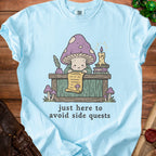 Light blue t-shirt with a mushroom character reading a scroll, text reads "just here to avoid side quests."