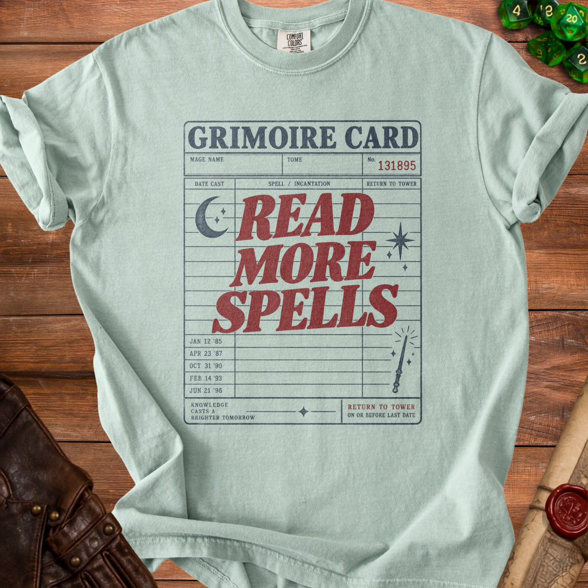 Light blue t-shirt with "Grimoire Card Read More Spells" graphic and library card details.