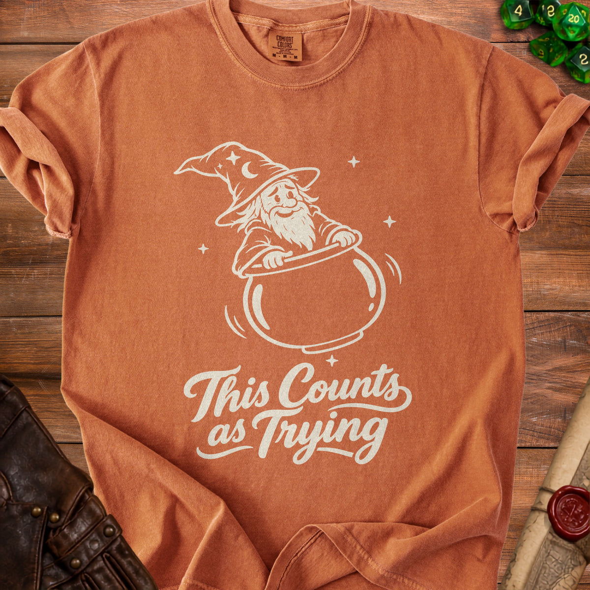 Orange t-shirt with white graphic of a wizard in a cauldron, text reads "This Counts as Trying".