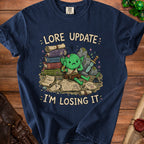 Navy t-shirt with a distressed graphic of a goblin and scrolls saying "Lore Update: I'm Losing It."