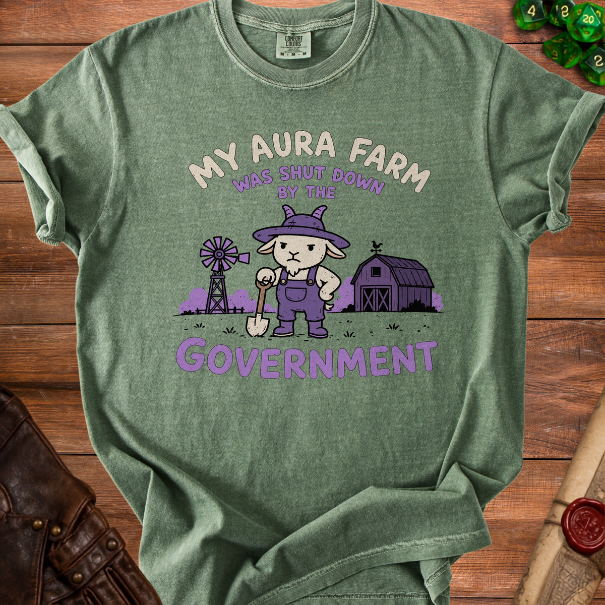 Green t-shirt with illustration of a goat holding a shovel, farm, and text "My Aura Farm Was Shut Down By The Government".