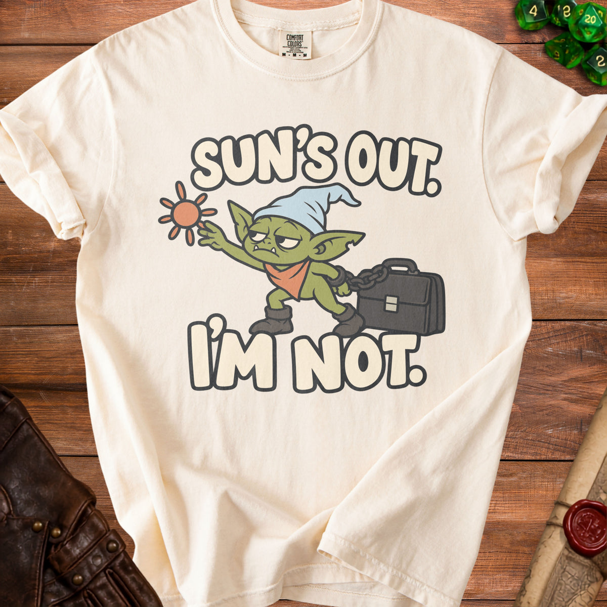 Cream t-shirt with a grumpy goblin graphic and text "Sun's Out. I'm Not."