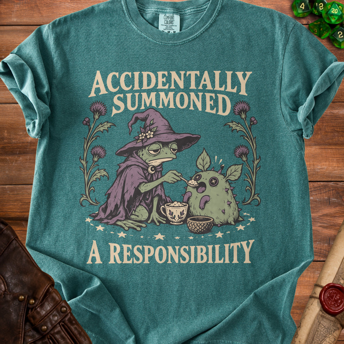 Green t-shirt with a frog wizard feeding a fluffy creature, "Accidentally Summoned A Responsibility" text.