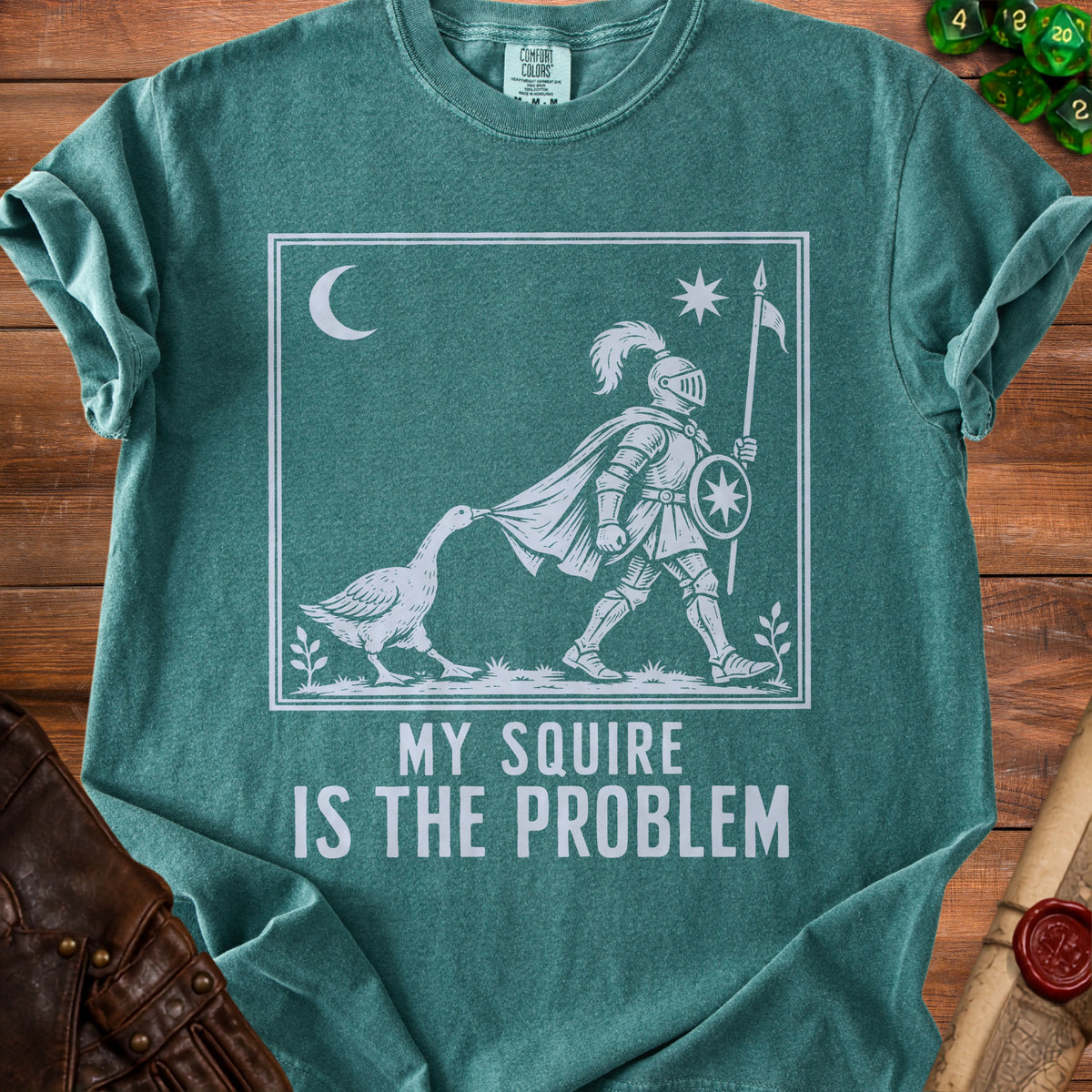 Green t-shirt with white graphic of knight and goose with text "MY SQUIRE IS THE PROBLEM".