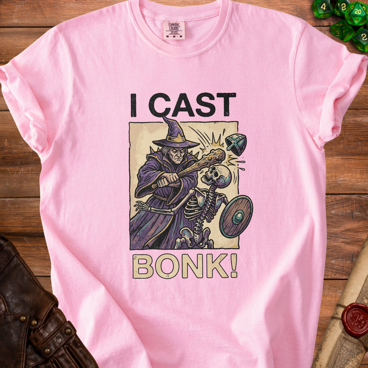 Pink t-shirt with illustration of wizard fighting skeleton, reads "I CAST BONK!".
