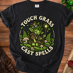 Black t-shirt with a green creature illustration saying "Touch Grass Cast Spells".