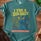 Teal t-shirt with wizard, skeletons, treasure chest graphic and text "I TOOK A SIDE QUEST AND ALL I GOT WAS A CURSE".