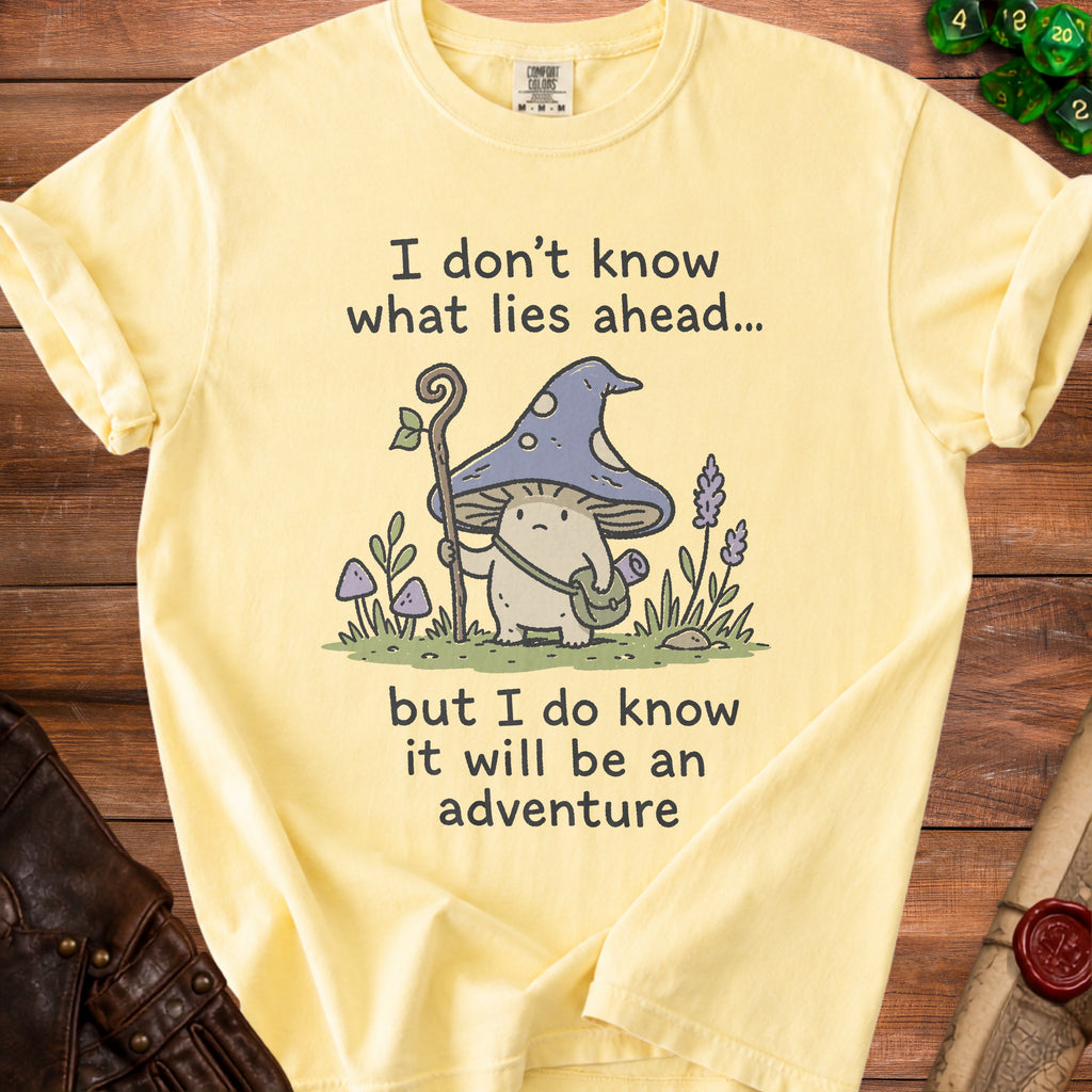 Yellow t-shirt with a mushroom character and text "I don't know what lies ahead... but I do know it will be an adventure".