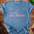 Blue t-shirt with pink text: "I HAVE SMALL AMBITIONS", "tiny cottage", "mushroom garden", "good soup", "gentle hauntings", "zero prophecies", "no visitors".