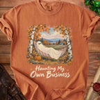 Orange t-shirt with a ghost in a hammock and text "Haunting My Own Business."