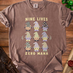 Brown t-shirt with nine illustrated cats in witch hats and "NINE LIVES ZERO MANA" text.